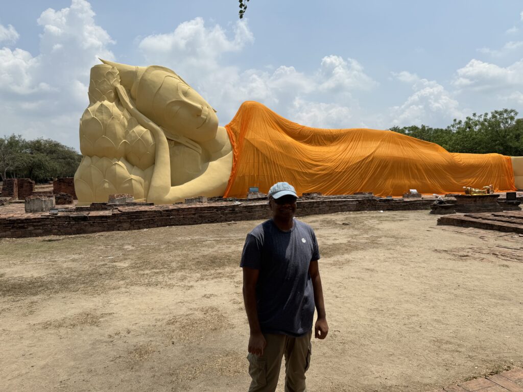 A large reclining Buddha statue covered with an orange cloth.